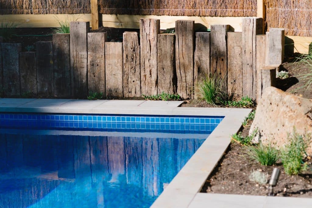 a retaining wall surrounding a custom concrete pool