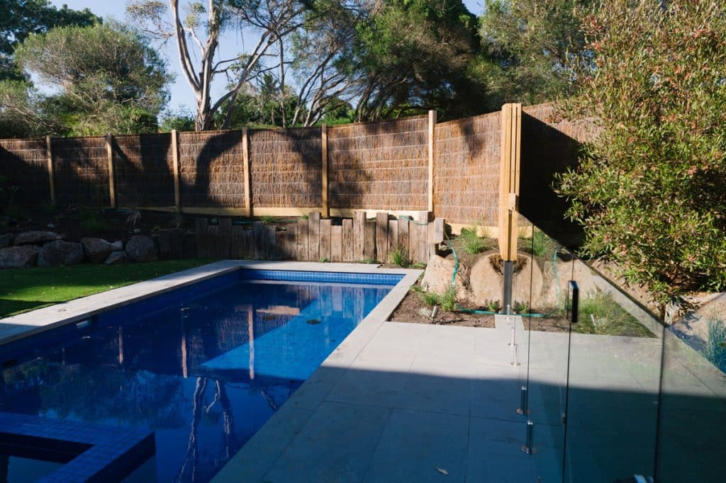 a glass wall encasing a inbuilt concrete pool and spa