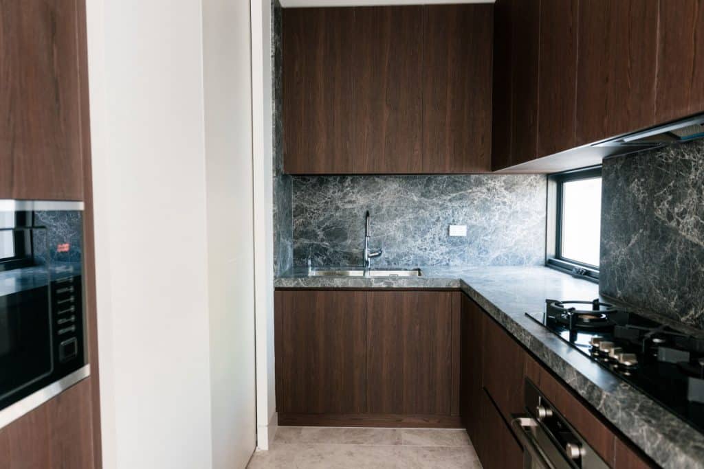 marble benchtop and splashback inside brown kitchen