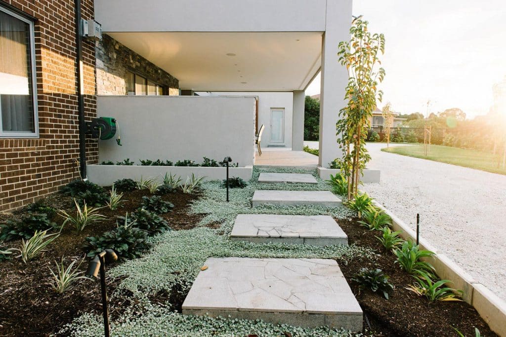 moss surrounding marble pavers in front of a custom front landscape